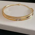 Dettaglio di un girocollo minimalista in metallo dorato lucido con finitura curva. - Oro