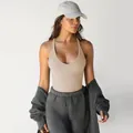 Women's khaki ribbed knit V-neck tank top styled with grey joggers and a zip-up hoodie - XS / Apricot