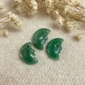 Macro shot of three hand-carved green aventurine crescent moon pendants on linen - Green Aventurine