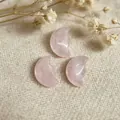 Close-up of hand-carved pink rose quartz crescent moon face charms for DIY jewelry making - Rose Quartz