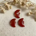 Macro shot of hand-carved natural red carnelian moon face pendants on white linen - Red Jasper
