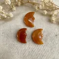 Three orange natural stone moon face pendants with detailed double-sided hand carvings - Red Aventurine