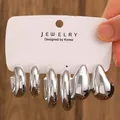 Three pairs of silver C-shaped chunky hoop earrings on a display card held by hand - 3-Pair Silver Minimalist Hoop Earrings Set / Silver (WG-0720)