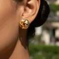 Exaggerated golden twisted knot stud earring with textured finish on model - Kc Gold 4054