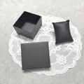 Vista detallada de una caja cuadrada negra para joyas con rayas texturizadas y cojín a juego - Negro