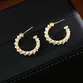 Dettaglio degli orecchini a cerchio a C in metallo dorato intrecciato con perle bianche - Oro 14K