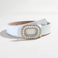 Detailed shot of white leather belt with gold buckle featuring pearls and rhinestones - White
