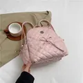 Rosafarbener gesteppter Mini-Rucksack mit Schleife vor stylischem Hintergrund - Rosa
