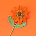 Handmade crochet sunflower with orange petals and green leaves on an orange background - Orange-colored Snow Five-seed Sunflower Branch (double Leaves)