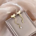 Detailed view of asymmetrical gold heart fringe earrings with sparkling crystals - Gold Heart Asymmetric Tassel