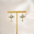 Macro view of gold Saturn planet and airplane earrings with sparkling zircon crystals - Gold Planet Airplane Pendant