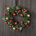 Kerstkrans met rode en gouden ballen, dennenappels en groen op donker hout - Stijl 25-26