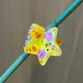Vibrant yellow star hair claw clip with smiley face on a natural green stem - Small Yellow Starfish