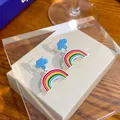 Blue cloud stud earrings with rainbow drop pendants on a beige textured jewelry tray - Cloud Rainbow Oil Drop Stud Earrings (E2715) / Blue