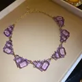 Elegant statement necklace featuring irregular purple emerald-cut crystals in a gold-tone setting - Necklace / Purple