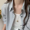 Detail view of a gold-plated pointed heart necklace with engraved stars on a model - Gold