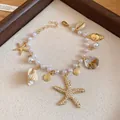 Detail showing a gold starfish and pearl beaded bracelet with various seashell charms - 45# Bracelet / Gold-White