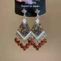 Detailed close-up of ethnic style crystal tassel earrings with pearls and red beads. - Streaming Flower Tassel (51# 925 Sterling Silver Earring Post-Gold) / Brown