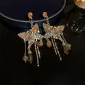 Detail shot of crystal butterfly earrings with long flowing amber tassels - Rhinestone Butterfly Style / Gold