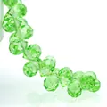 Vibrant emerald green faceted K9 crystal beads in a dynamic S-curve arrangement on white - Fruit Green / 6mm (approximately 87 Beads Per Strip)