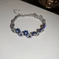 Detailed close-up shot of sparkling blue and white flower bracelet on textured white surface - Blue White Flower