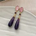 Close-up of elegant purple teardrop dangle earrings with pink oval stone and gold accents - Waterdrop-Purple