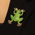Schicke Brosche in Froschform mit grünen Strasssteinen auf dunkler Kleidung - Frosch / Grün