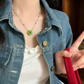 Bunte Perlenkette mit grünem Blumenanhänger an weiblichem Model in einer Jeansjacke. - Grün