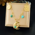 Collier doré avec lune, hibou et pierres turquoise sur un support de bijoux - N3756