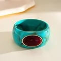 Dettaglio di un bracciale rigido vintage in acrilico turchese marmorizzato con pietra rossa. - Stile Acrilico con Strass / Turchese e Rosso Vino