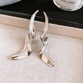 Detailopname van geometrisch gedraaide metalen oorbellen met glanzende zilveren afwerking - Vloeibaar Metaal Gestroomlijnd (62#)