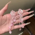 Close-up of pink beaded tassel earrings with flower charms for a sweet vacation look - Pink