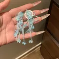 Detailed handheld shot of light blue floral beaded tassel earrings for beach vacations - Blue