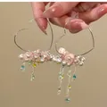 Detailansicht der herzförmigen Creolen mit bunten Quasten und rosa Blüten - Herz-Quaste-Stil / Silber Bunt