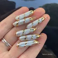 Hand holding natural baroque rectangular pearl pendants with golden spiral metal edges - Spiral Edged Long Pearl