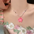Detailed view of a beaded necklace featuring a vibrant pink flower pendant on a model's neck. - Pink