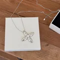 Close-up of a silver quilted cross star pendant necklace displayed on a white box - Silver