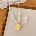 Dettaglio macro di una collana di perle con fiore giallo e ciondoli a forma di stella - Giallo