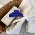 Close-up of a large royal blue hair claw clip with a glossy finish on a white shirt - Sapphire Blue