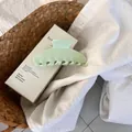 Detailed view of large mint green jelly shark clip on a white linen shirt background - Milky Green