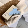 Detail of light blue glossy hair claw clip on white shirt and woven basket background - Sky Blue
