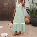 Dettaglio dello scollo a V con bordo in pizzo bianco sull'abito estivo a righe - S / Verde