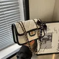 Cream quilted chain crossbody bag with black trim and elegant striped ribbon detail - White