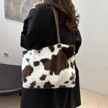 Plush shoulder bag featuring brown and white cow print with a leather strap - Coffee