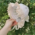 Detail of baby lace bonnet featuring delicate floral ruffles and a silk butterfly bow - Beige Bow Lace Hat