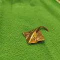 Macro shot of antique brass stingray figurine with detailed texture on green cloth - Manta Ray