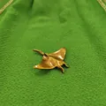 Macro detail of a vintage golden brass manta ray ornament with textured wings - Stingray