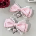 Detailansicht der rosa Satinschleifen mit weißer Spitze und silbernen Herz-Kreuz-Anhängern - Rosa Herz