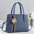 Deep blue-grey textured leather tote bag with gold hardware and floral tassel charm - Blue