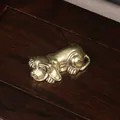 Detailed close-up of antique brass dog figurine on a dark textured wooden surface - Overtime Dog